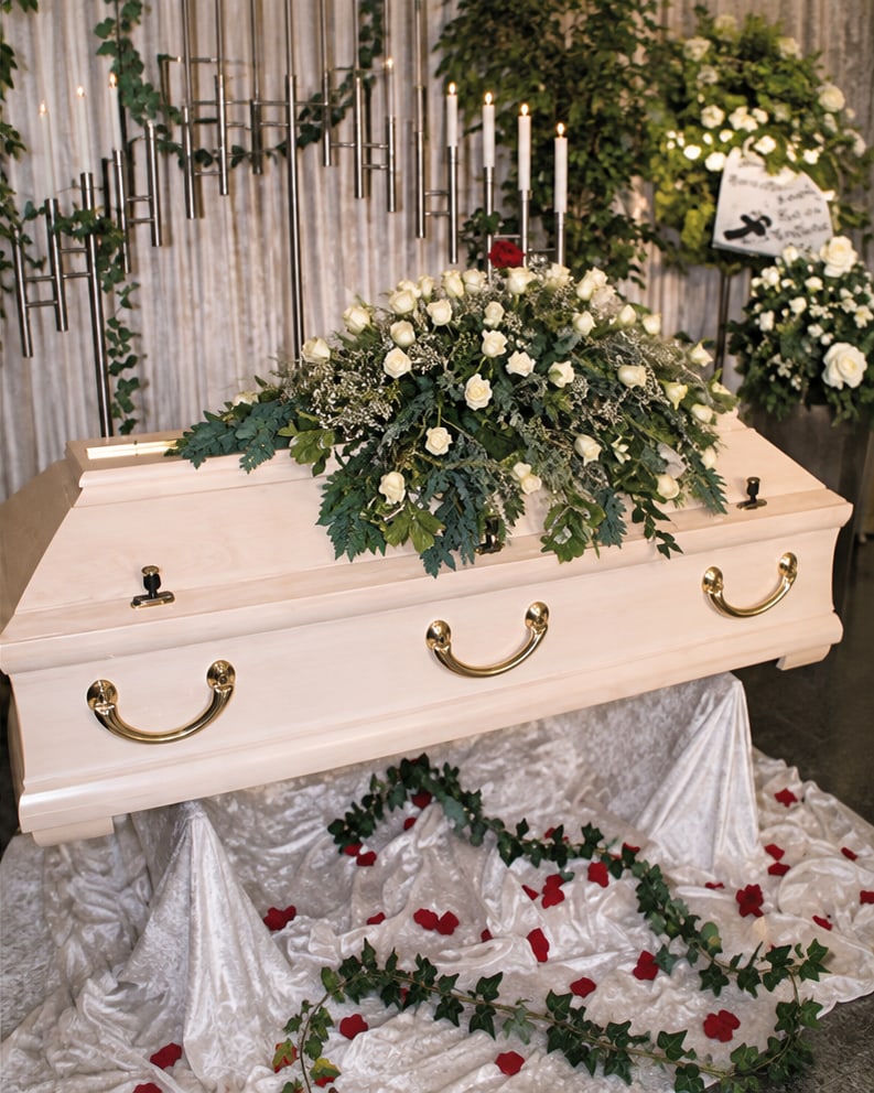Heller Sarg mit Blumenschmuck